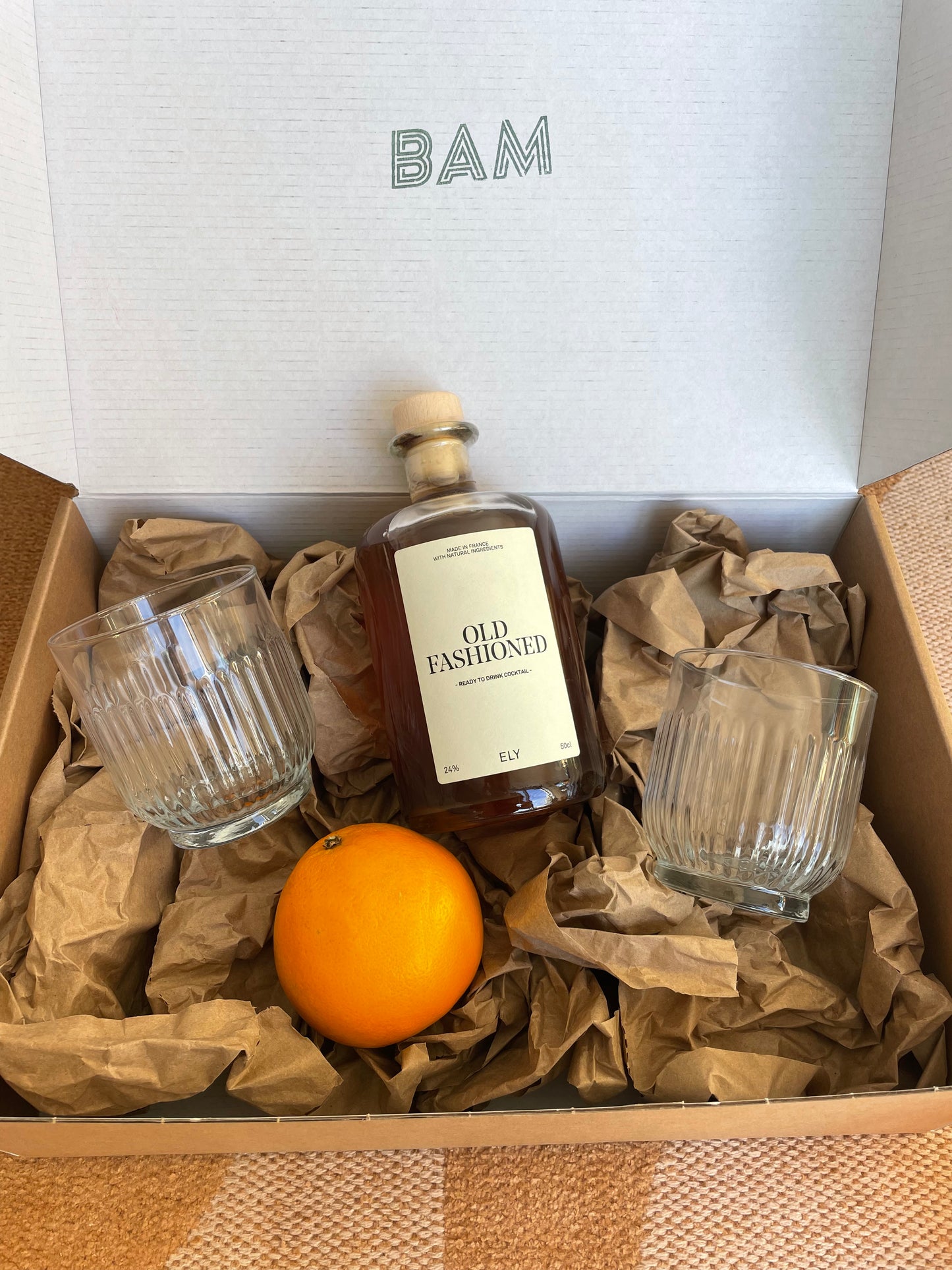 Coffret Old School avec bouteille de cocktail Old Fashioned, verres vintage et orange fraîche.