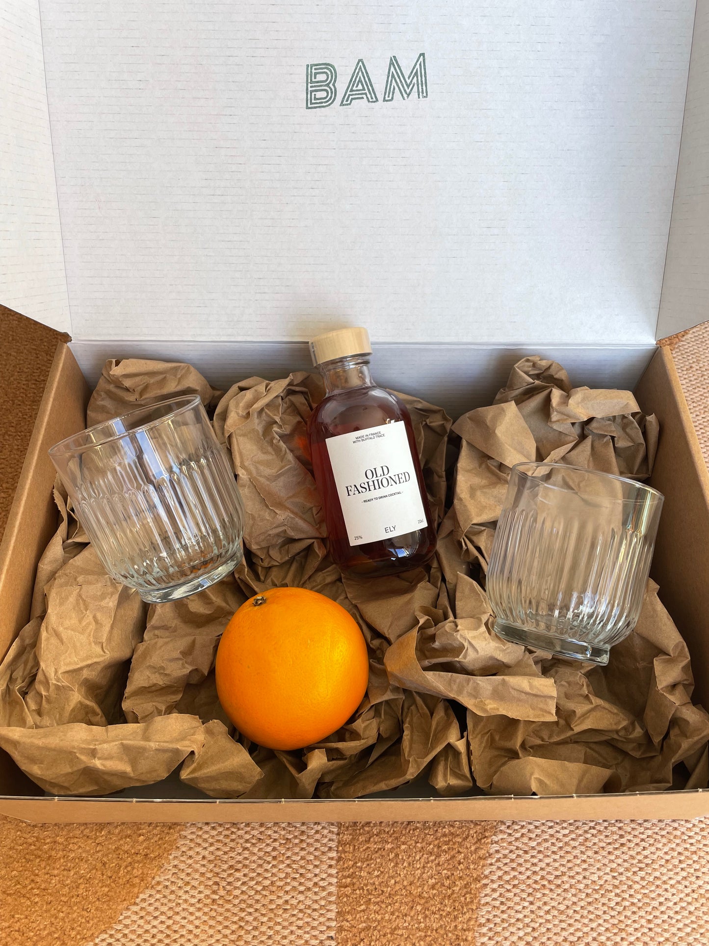 Coffret Old School avec bouteille de cocktail Old Fashioned, verres vintage et orange fraîche.