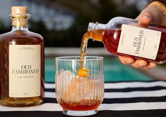 Verre vintage garni de glaçons, de cocktail Old Fashioned, et d’une tranche d’orange.