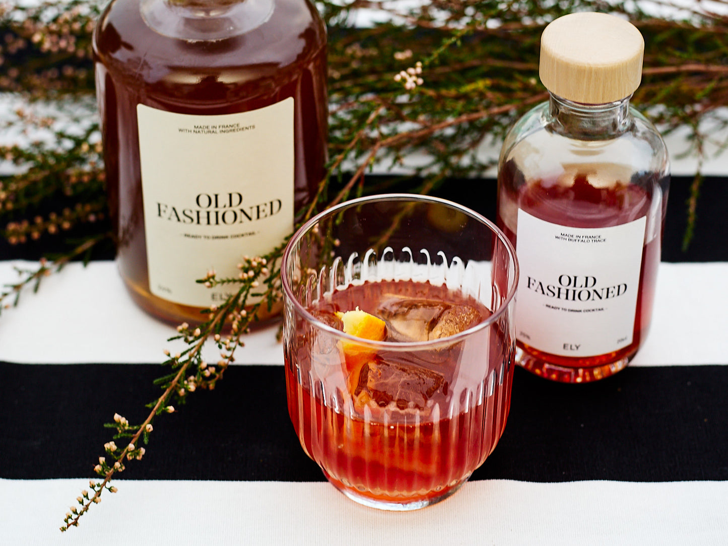 verre ciselé garni de glaçons et tranche d’orange, avec 2 cocktails Old Fashioned en bouteille
