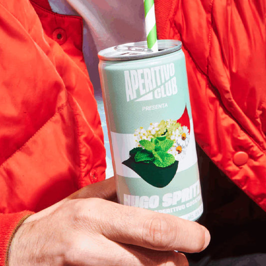 homme vêtu d'un tee shirt blanc et bombers rouge tenant une canette de hugo spritz avec paille à rayures vertes