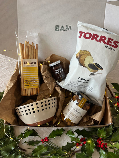 Coffret cadeau épicerie fine Maison BAM ouvert, contenant chips au caviar, olives vertes, gressins, tartinade figues–olives et bol BAM dans un écrin kraft décoré de bruyère et ficelle vert/blanc.
