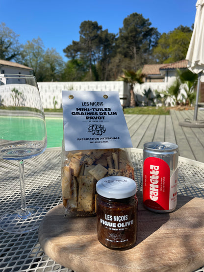 Pack apéro Red Crush de Maison BAM – vin rouge en canette, tartinade figues & olives, tuiles aux graines de lin, sur fond d’été ensoleillé avec vue sur les pins