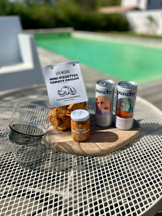 Pack apéro Sunset de Maison BAM – mocktails orange sanguine & pêche gingembre,  tartinade chèvre & tomate, pizzettas, pris en photo sur une terrasse au bord de la piscine
