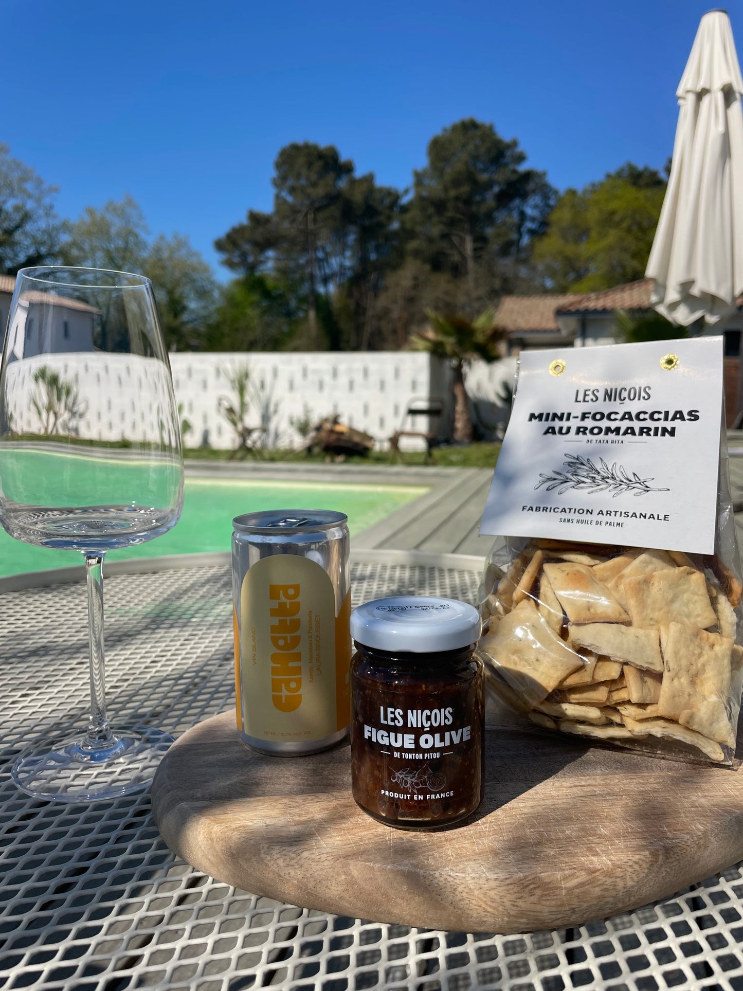 Pack apéro White Bliss de Maison BAM – vin blanc en canette, tartinade figues & olives, focaccias, ambiance élégante en extérieur, vue sur les pins
