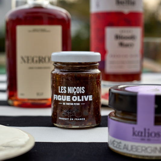 tartinade figue olive des nicois disposé sur une table avec du negroni en bouteille et du mezze aubergines