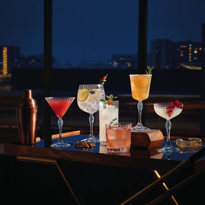 desserte vintage avec verres a pieds garnis de cocktails et décorations, shaker, passoire à cocktails, vue sur la ville