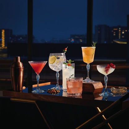 desserte vintage avec verres a pieds garnis de cocktails et décorations, shaker, passoire à cocktails, vue sur la ville