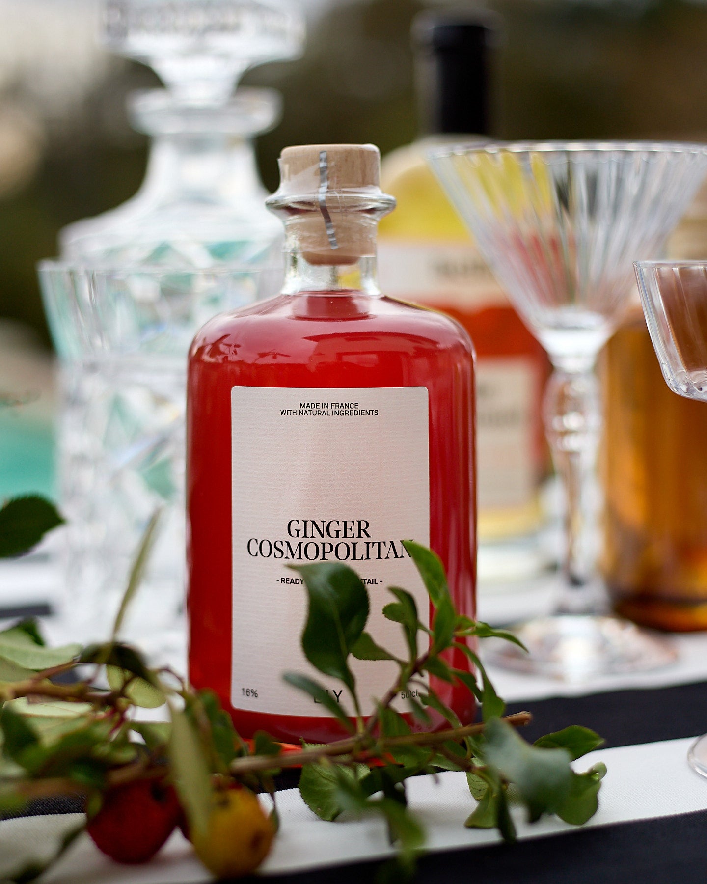 bouteille de cosmopolitan ready to drink posé sur une table avec branches de décoration