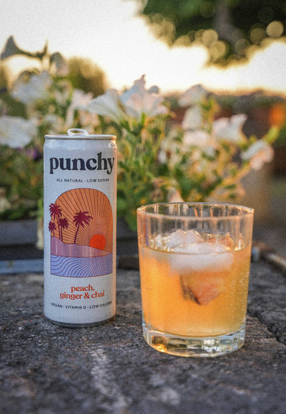 canette sans alcool peche gingembre et chaï servi dans un verre ciselé avec des glaçons au jardin