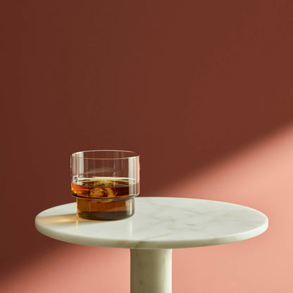 verre à whisky ou à cocktail, avec glaçons, posé sur une table en marbre blanc