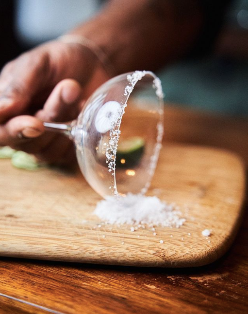 main qui givre un verre à cocktail sur une planche en bois 
